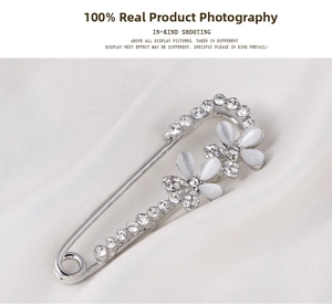 Detailed view of silver flower brooch with white opal petals and sparkling zircon inlay