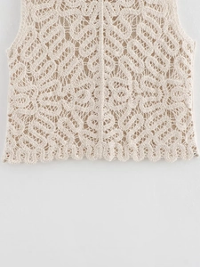 Detailed close-up of intricate hollow-out crochet pattern on cream knitted sleeveless top