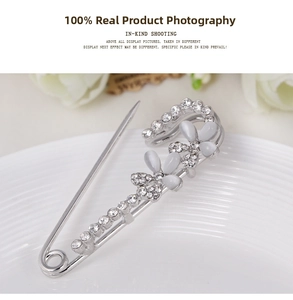 Macro detail of silver flower brooch with white rhinestones and opals on ceramic plate