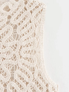 Macro shot of off-white crochet knit texture showing intricate floral cutout patterns