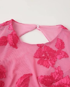 Détail de robe de soirée rose en tulle avec broderie florale 3D et bouton goutte au dos