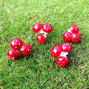 Close-up of red foam mushroom ornaments with white dots scattered on a lush green lawn