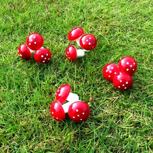 Detail of miniature red mushroom ornaments with white spots on green garden lawn