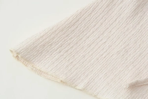 Vista dettagliata della trama del tessuto seersucker bianco sporco con cucitura overlock