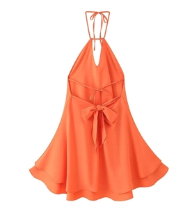 Detail of bright orange halter dress featuring open back with double bow tie and flowy hem