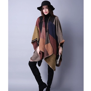 Detail of color-block knit poncho showing thick textured material and fine hem stitching