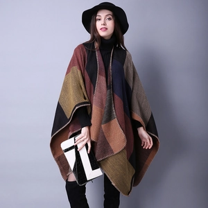 Detail of multi-color geometric knit poncho showing thick texture and stitching quality