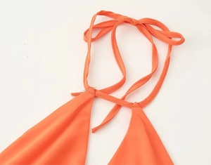 Detail view of vibrant orange halter neck straps and stitching on lightweight woven dress