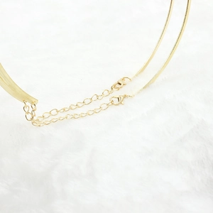 Macro detail of gold double-layer punk necklace featuring lobster clasp and extension chain