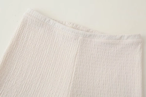 Primo piano dei pantaloni plissettati bianchi a vita alta con elastico in vita estensibile