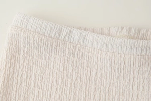 Dettaglio del tessuto plissettato ad alta densità con vita elastica per pantaloni