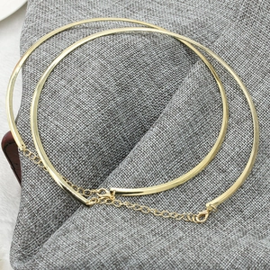 Detailed view of golden flat snake chain necklace with lobster clasp on linen texture