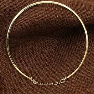 Detail view of a chunky gold metal collar necklace with extension chain and lobster clasp