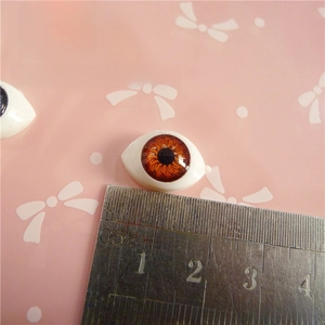 Detailed view of 12mm brown acrylic doll eyes with ruler for size reference