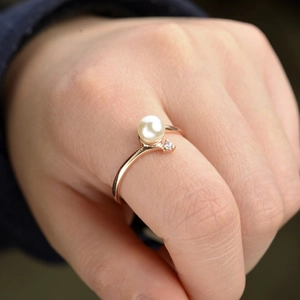 Elegante anello di perle in oro rosa con zircone indossato sul dito di una donna