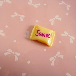 Macro detail of yellow resin candy accessory with Sweet text for DIY crafts