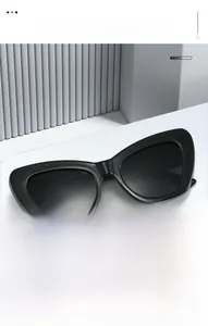 Detailed view of classic black cat-eye sunglasses with thick resin frames on a white pedestal