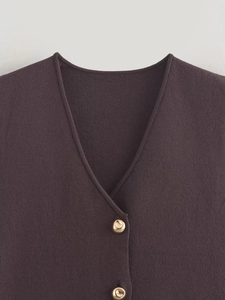 Close-up of V-neck knit vest featuring polished gold metal buttons and premium texture