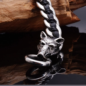 Macro shot of twin wolf heads clasp on a braided leather bracelet with mirror reflection