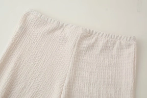 Vista dettagliata della fascia elastica in vita e del tessuto plissettato color panna