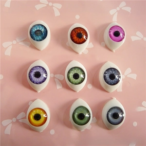 Detailed view of nine colorful acrylic doll eyes in multiple iris shades on pink background