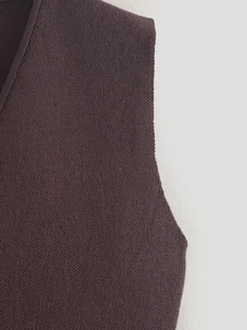 Close-up of V-neckline and fine knit texture on dark purple sleeveless vest with ribbing