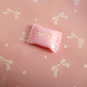 Macro view of a pink resin candy-shaped accessory with engraved Sweet text for DIY crafts