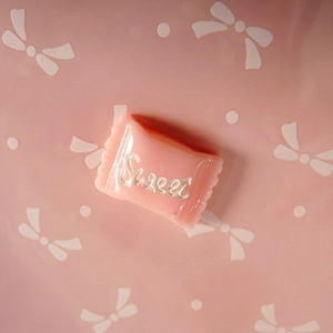 Detail shot of light pink resin candy charm with Sweet text for DIY hair and shoe accessories