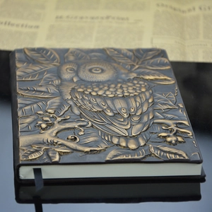 Macro shot of 3D embossed owl design on vintage style faux leather notebook cover