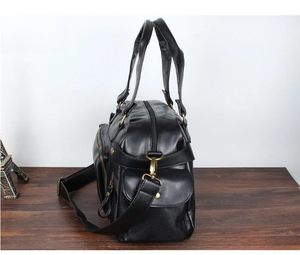 Side view of large black PU leather travel bag with bronze hardware and adjustable strap