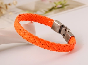 Detail of vibrant orange braided leather bracelet with silver metal press buckle closure