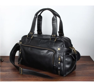 Detail of black PU leather travel bag showing texture, front zipper, and adjustable strap