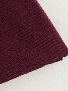 Gros plan du tissu en maille bordeaux montrant la texture fine et les détails de qualité