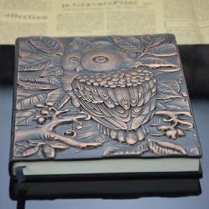 Close-up of vintage bronze owl relief embossing on retro notebook cover with texture