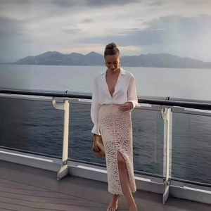 Chic white V-neck shirt and beige crochet knit maxi skirt set with elegant ocean view