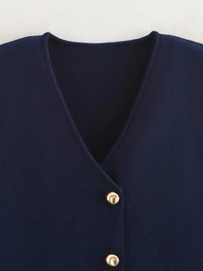 Detailed view of navy knit vest with elegant gold dome buttons and V-neckline texture