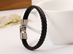 Close-up of woven black leather bracelet with matte metal buckle on a ceramic cup