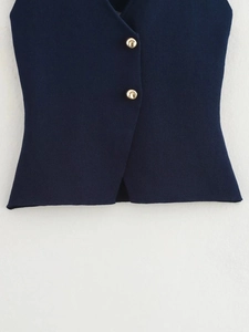 Detail of navy knit vest showing textured fabric and polished gold metallic buttons