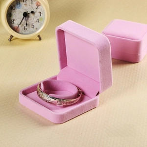 Pink velvet jewelry box detail showing a silver embossed bracelet on a soft cushioned interior