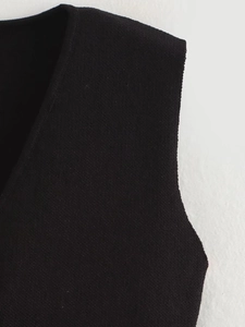 Close-up of V-neck and underarm stitching on this black minimalist knit vest