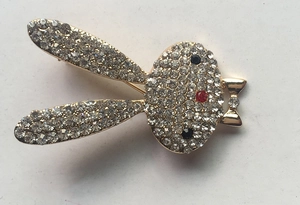 Detailed view of a golden rabbit brooch with sparkling rhinestones and a bow detail