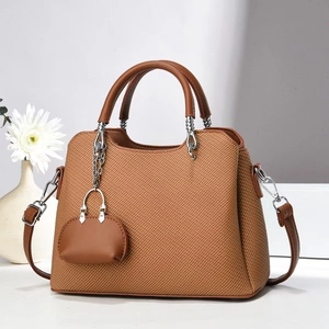 Close-up of brown woven texture handbag with leather handles and mini bag pendant