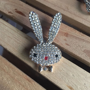 Detailed view of a gold rabbit brooch fully inlaid with sparkling rhinestones on wood