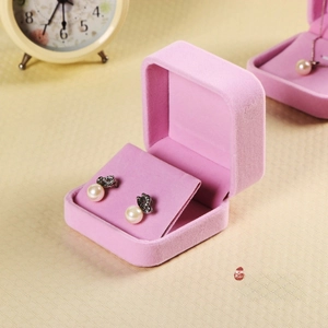 Pink velvet jewelry box detail featuring pearl earrings with black bow accents