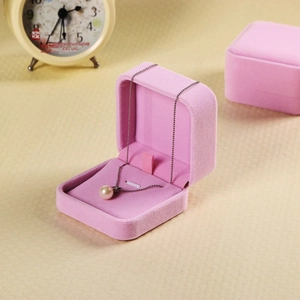 Pink velvet jewelry boxes for necklaces and pendants on a textured beige background