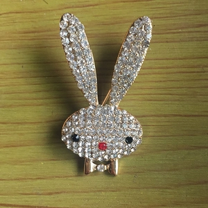Close-up of golden bunny brooch with sparkling rhinestones on natural wood surface