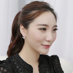 Detailed close-up of daisy floral stud earring with marquise cubic zirconia on ear