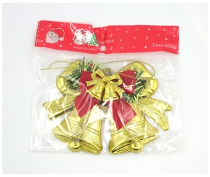 Golden embossed Christmas bells with red bow and green pine needles in bag packaging