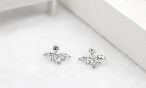 Macro detail of silver marquise cubic zirconia floral stud earrings on soft white fabric