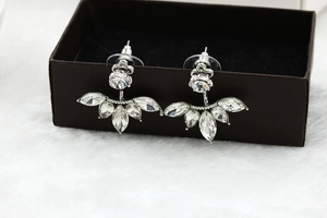 Close-up of petal-shaped silver earrings with marquise zircon stones on a jewelry box